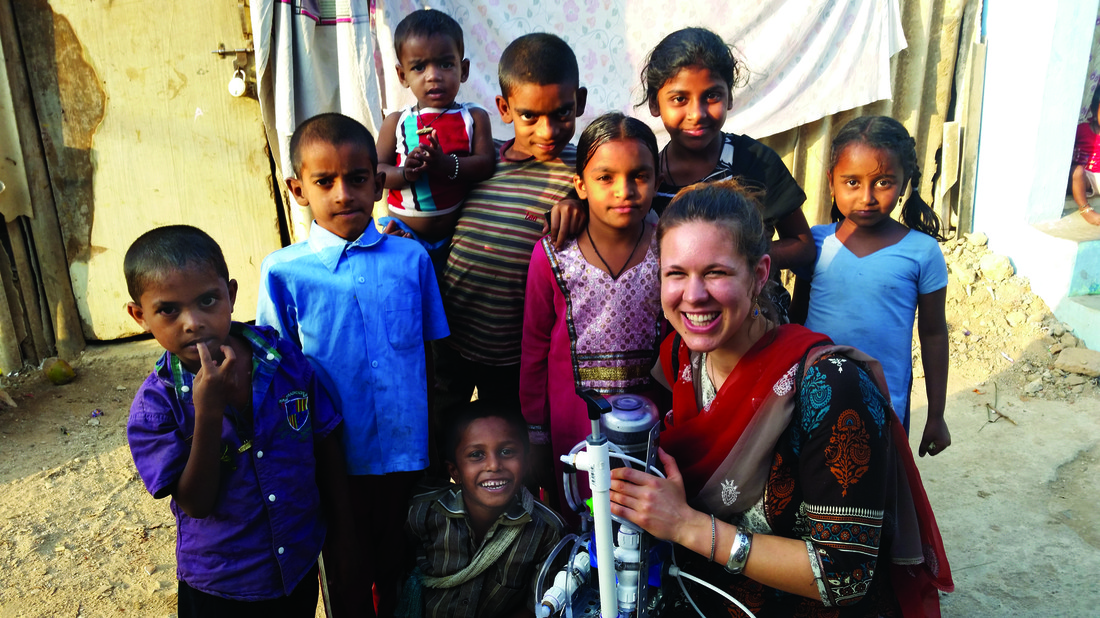 Image of student Kaylea Brase and children in Bangalore. She is holding the water filtration device she developed.