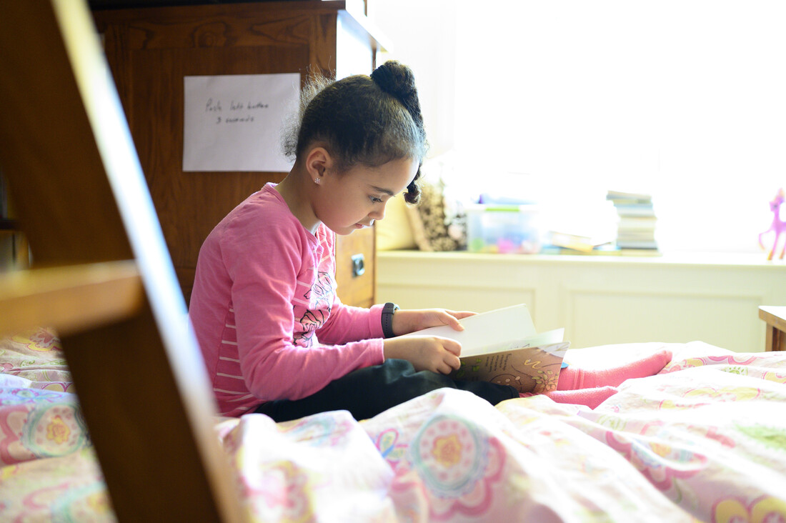 Young girl sitting on her bed reading