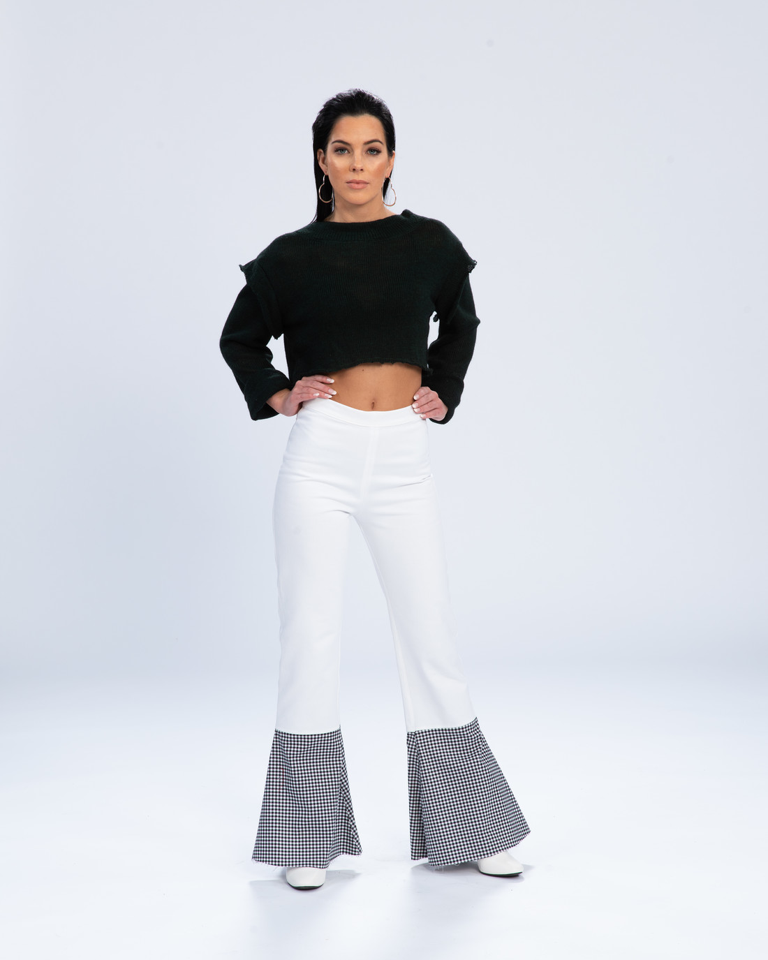 Woman in cropped black sweater with white and print flared pants