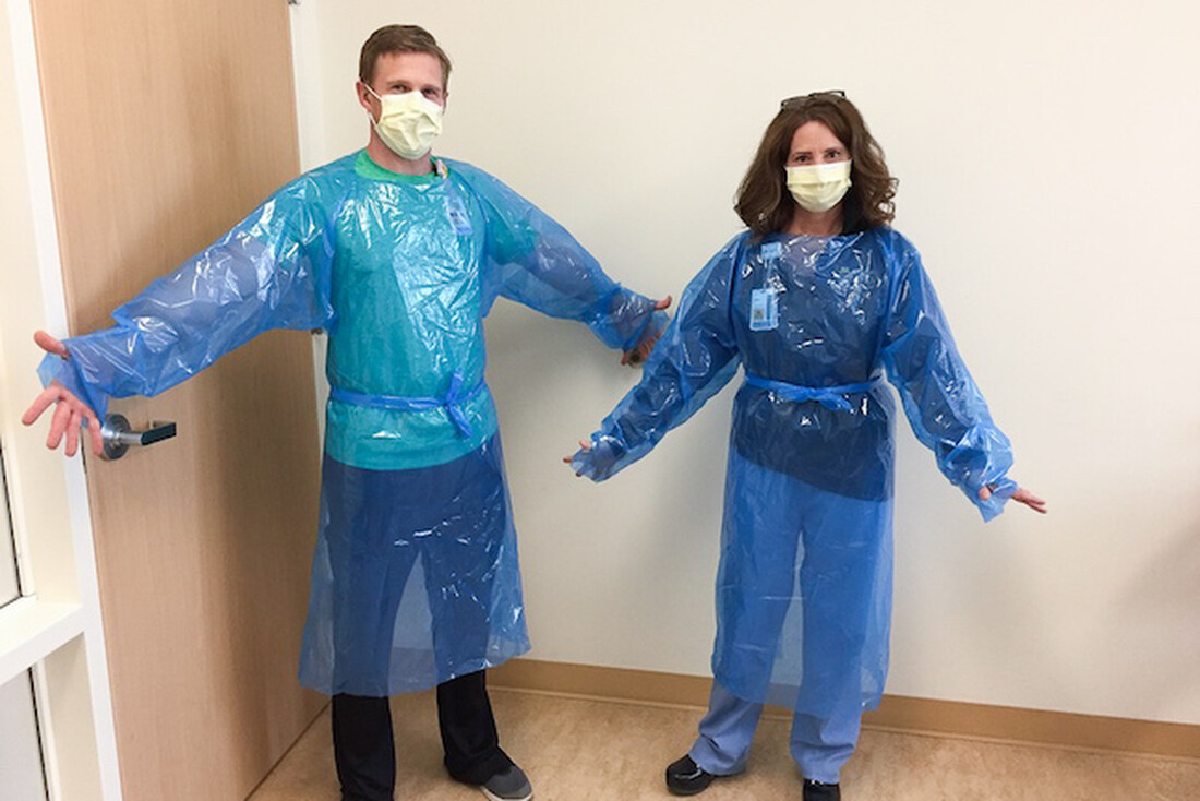 Two people modeling isolation gowns