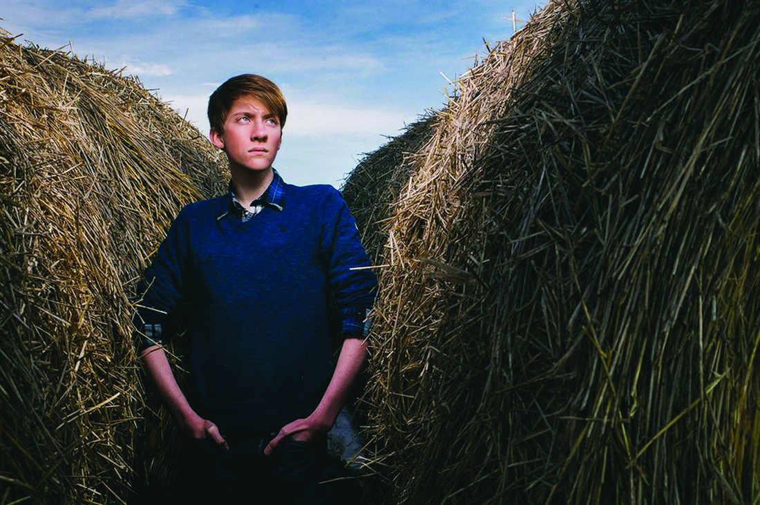 U of M student Justin Oakland standing in a hay field