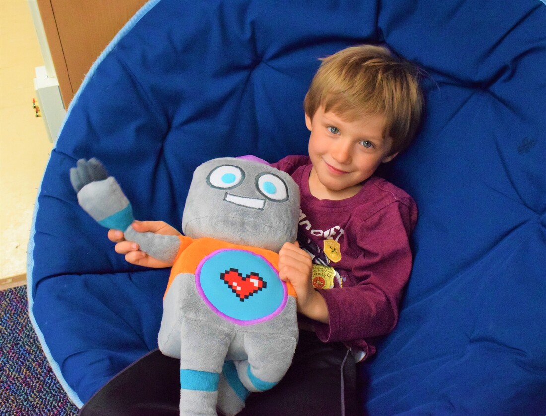 A boy holds a plush robot