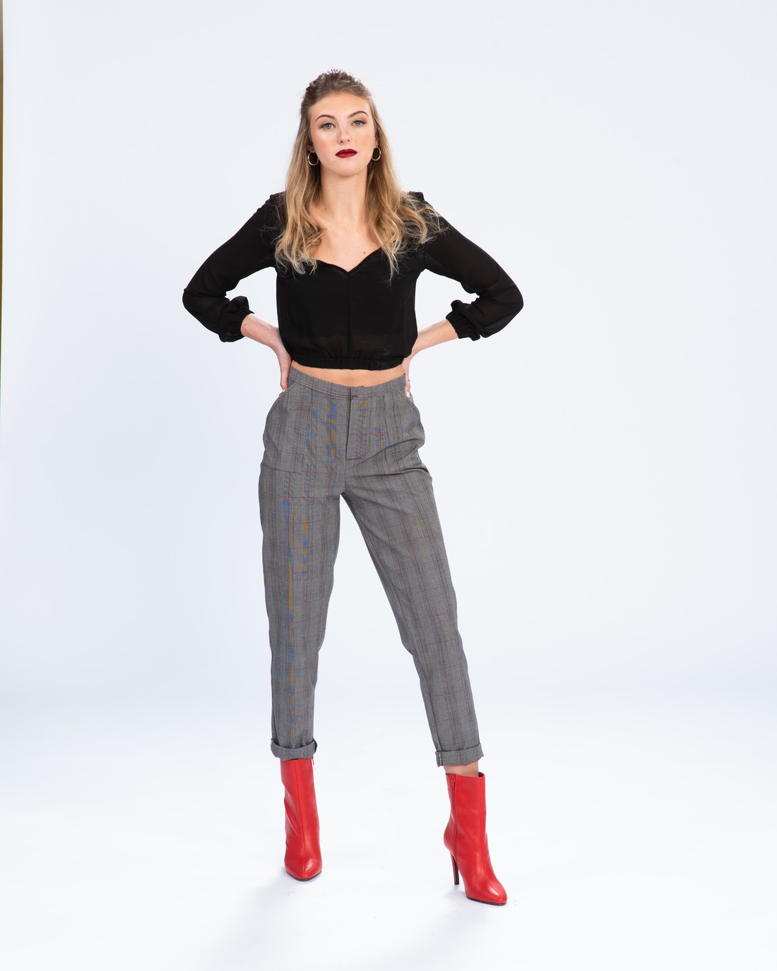 Woman in black top, grey cropped pants, red boots