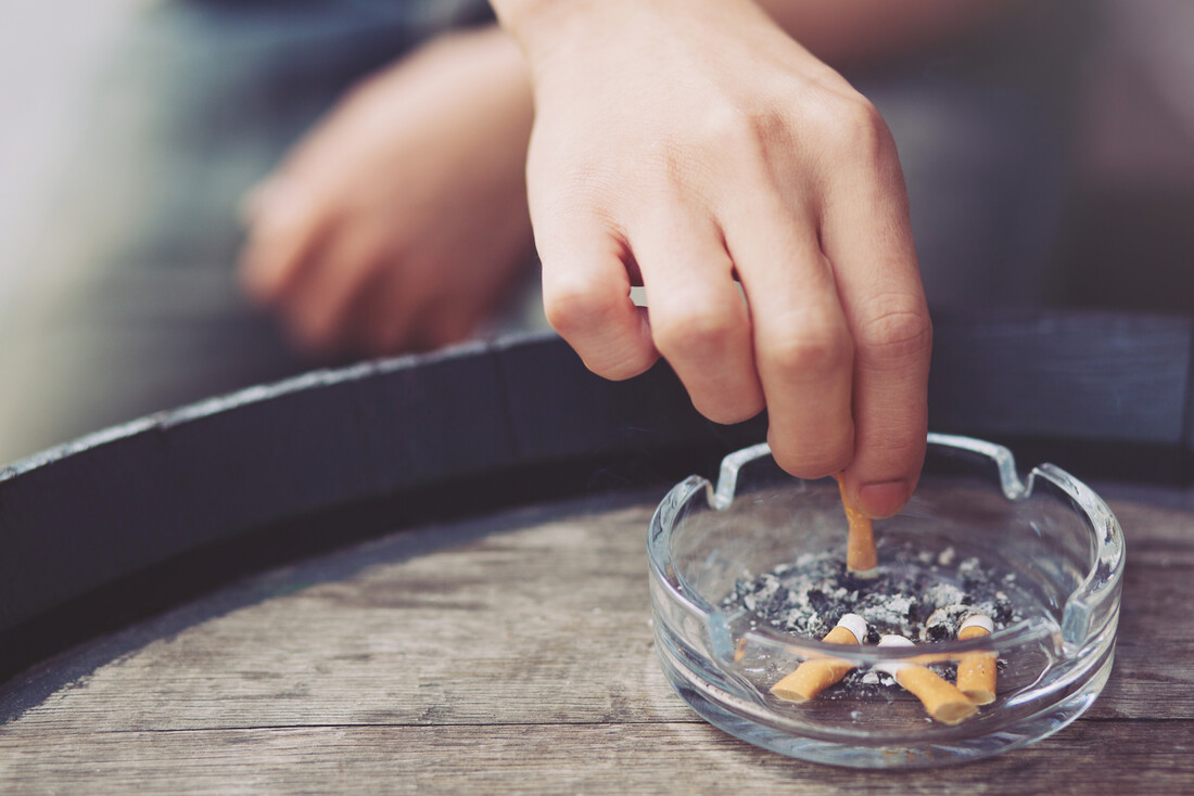 Hand of person tamping out a cigarette in an ashtray